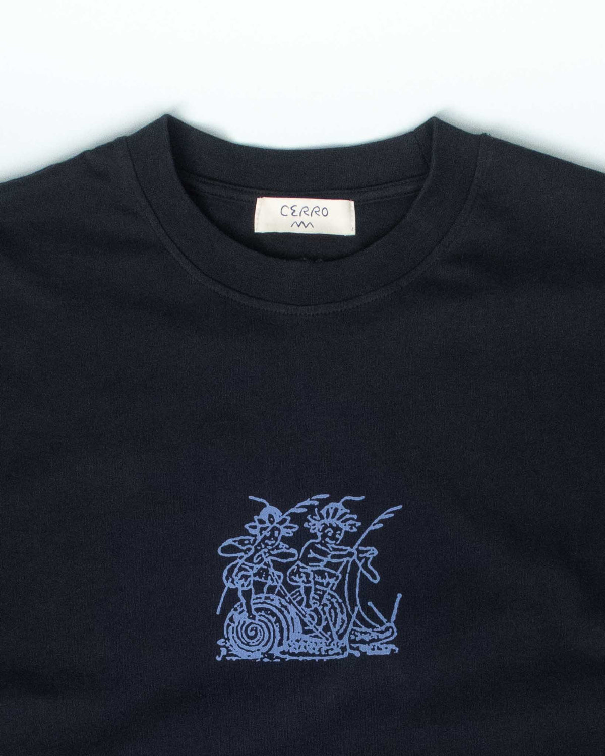 A close-up of a black crewneck t-shirt featuring a light blue embroidered graphic of a stylized figure on a snail on the chest. The brand label 'CERRO' is visible.